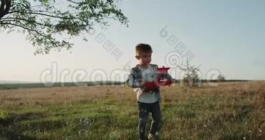 一个三岁的可爱男孩在<strong>大</strong>自然的气泡中行走，拿着一架红色的<strong>大飞机</strong>。